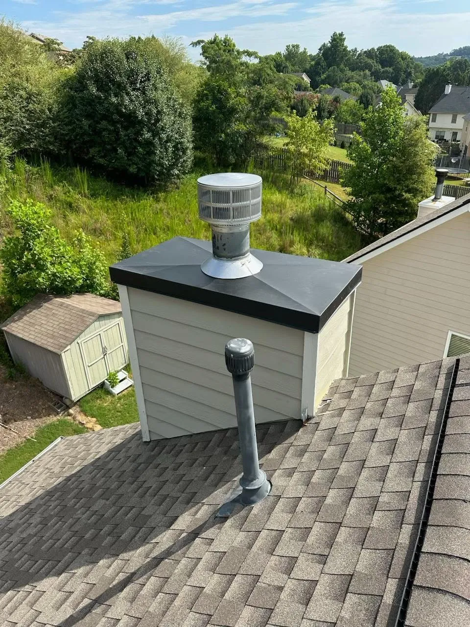 Rooftop chimney enclosure and vent terminations above a shingle roof