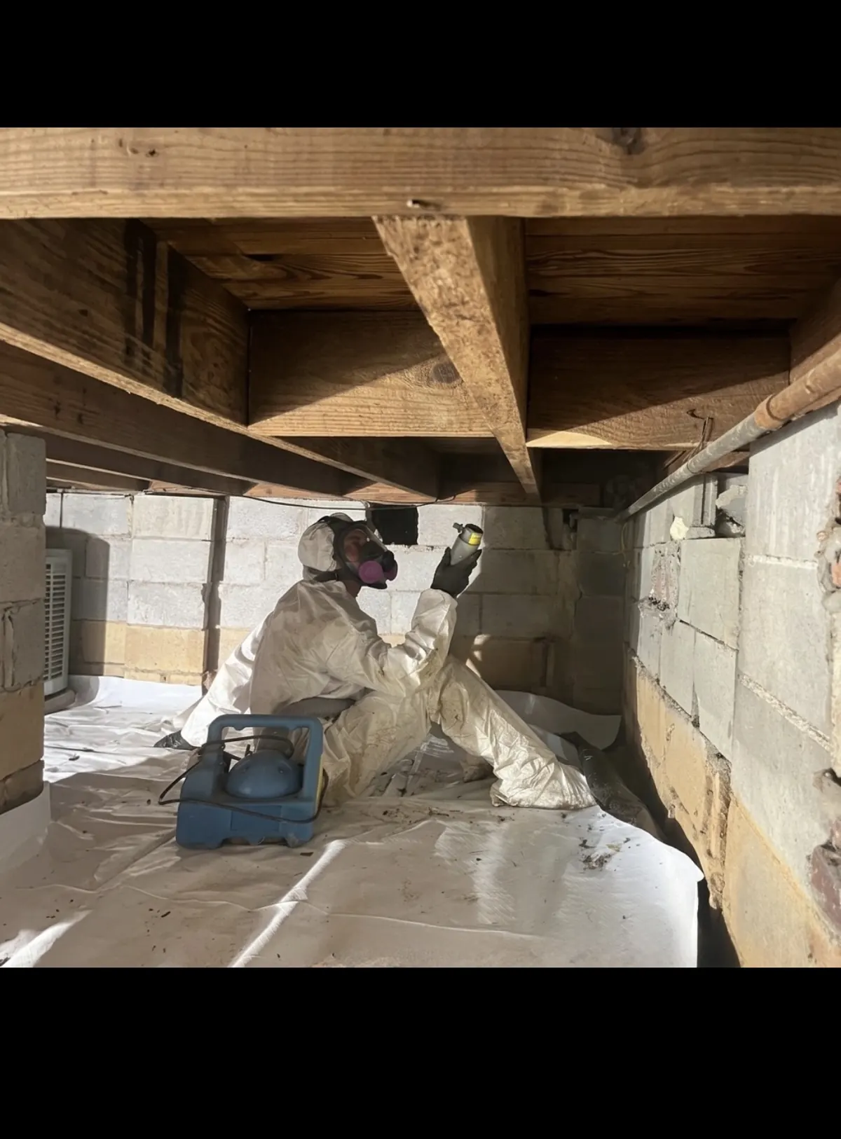 ASAP Pro mold technician in full PPE inspecting joists and subfloor inside a crawlspace in Oklahoma City