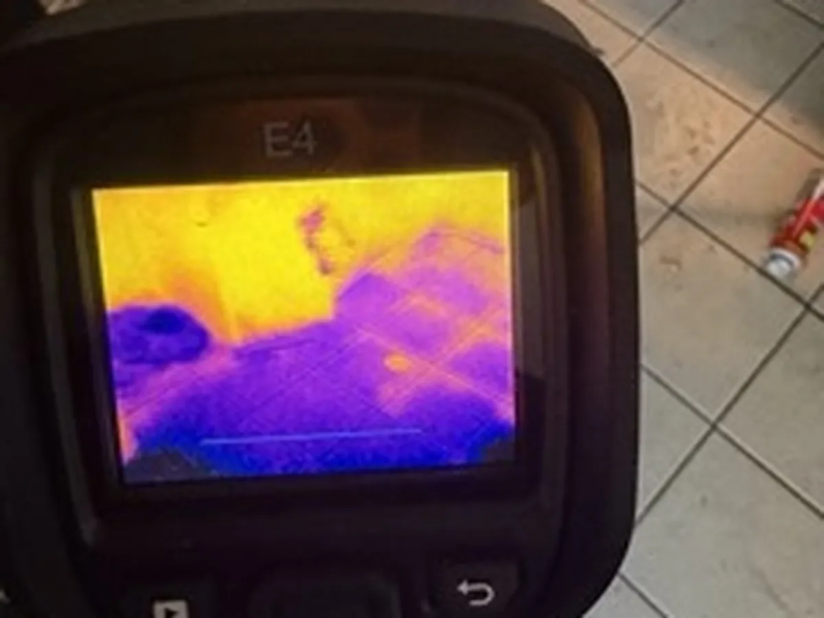 Thermal imaging camera showing hidden moisture spreading under tile flooring during an Oklahoma City water damage inspection